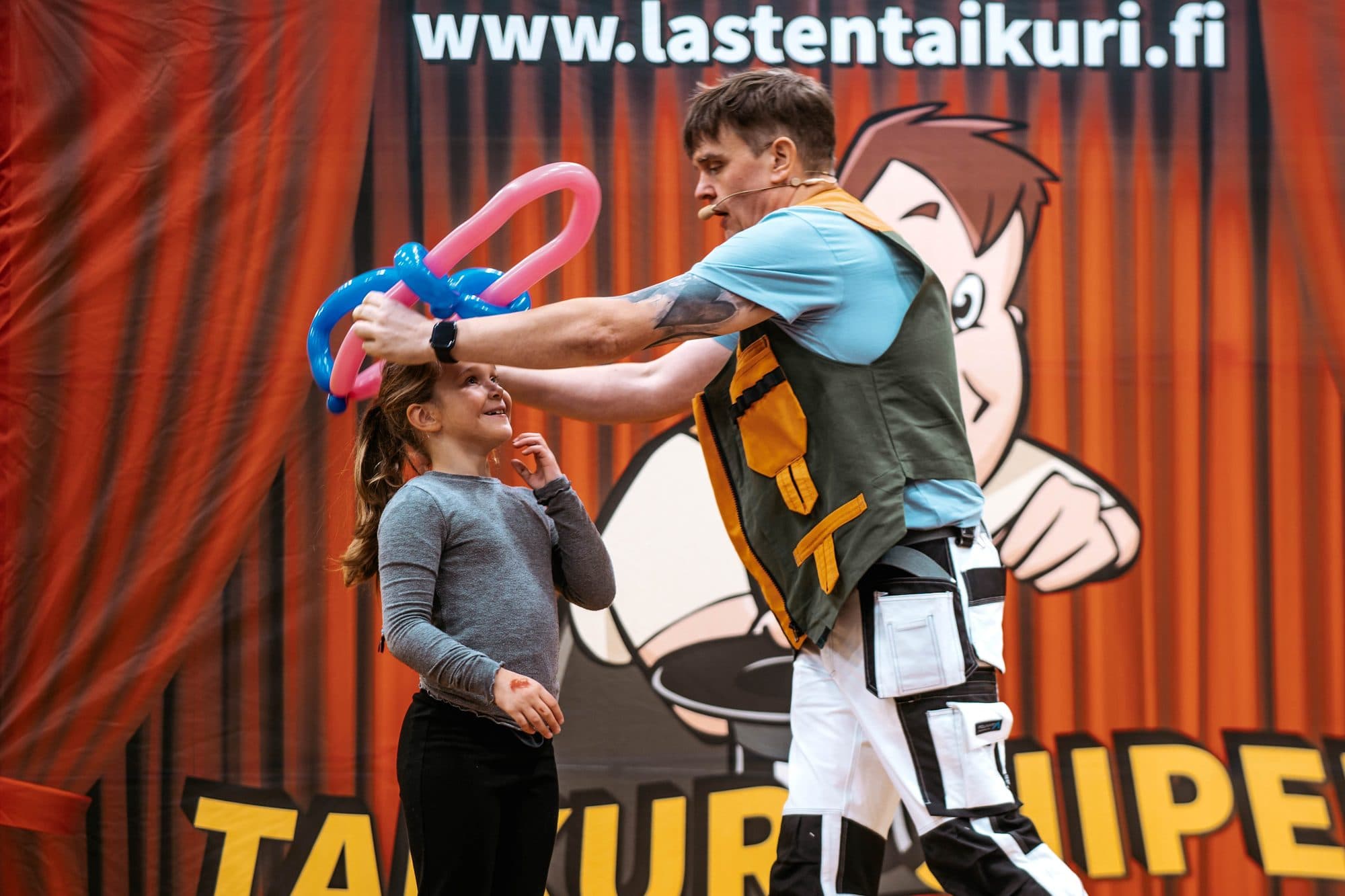 Lapsi avustaa lavalla ilmapalloteoksen tekemisessä