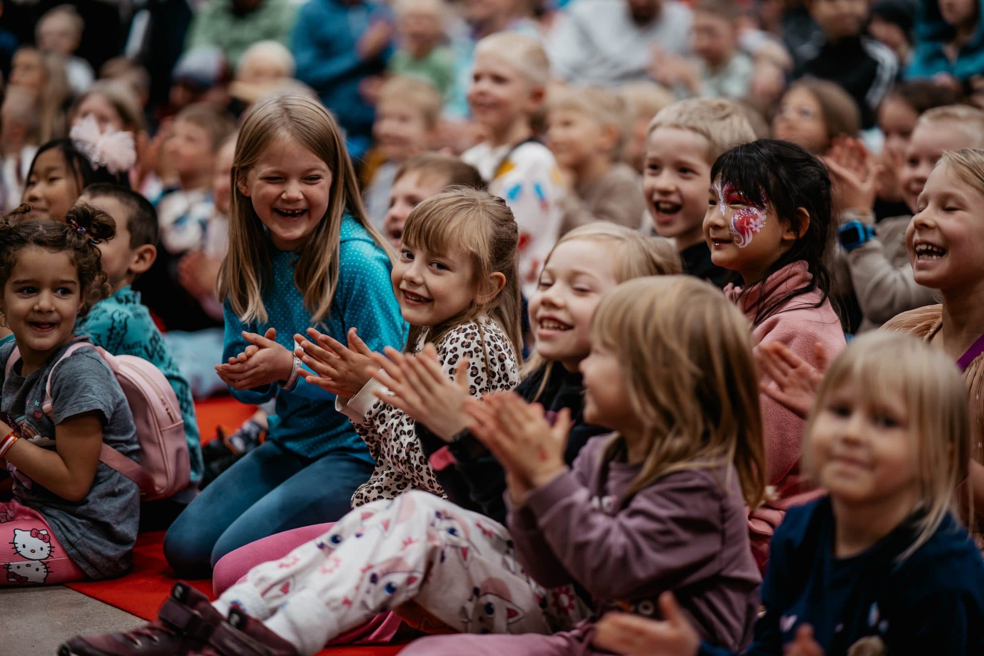 Lapset taputtavat ja nauravat lattialla istuen